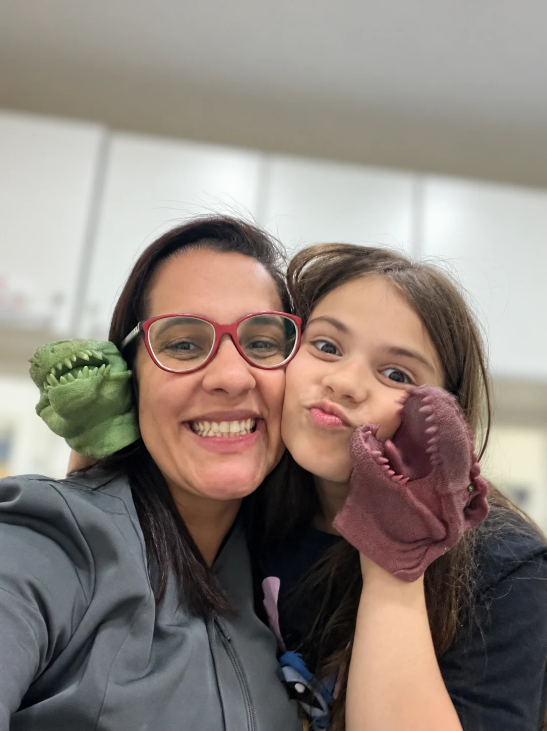 Dra. Anne e uma menina fazendo careta com dinossauros de brinquedo ao lado do rosto.